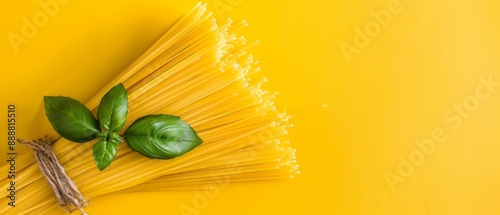  A flat lay of untested pasta and basil leaves against a yellow backdrop , arranged on a yellow surface