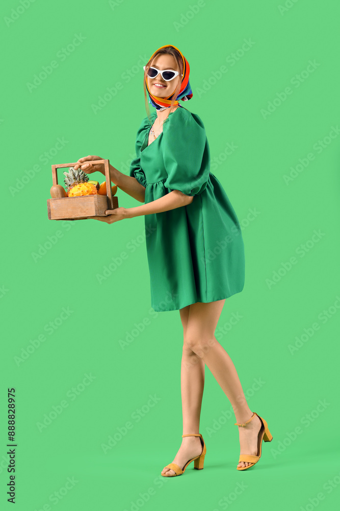 Pretty young woman with basket of exotic fruits on green background Pretty young woman with basket of exotic fruits on green background