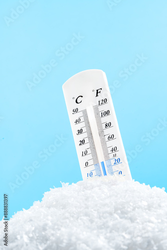 Thermometer Measuring Cold Temperature in Snow against blue background