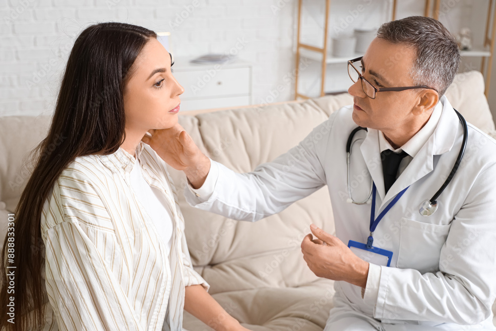 Mature doctor examining neck of ill young woman at home Mature doctor examining neck of ill young woman at home