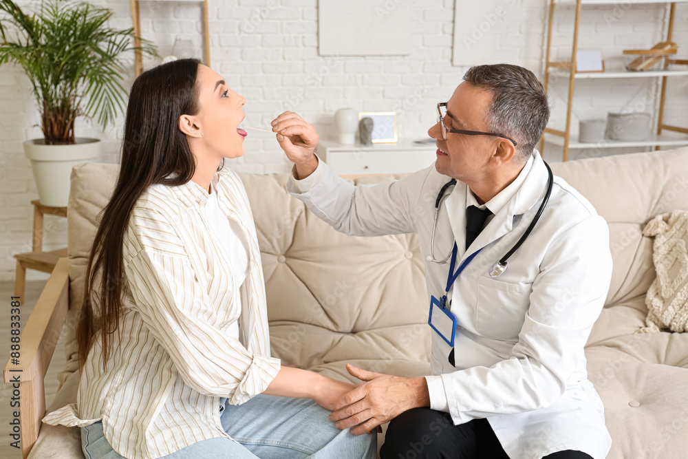 Fototapeta premium Mature doctor examining throat of ill young woman at home