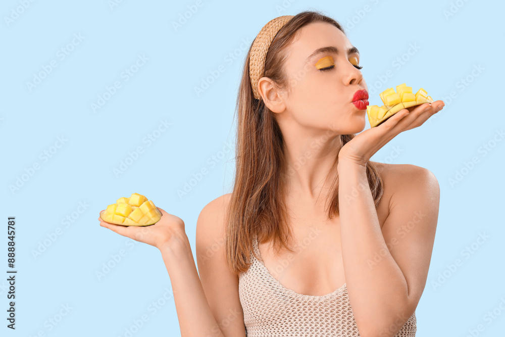 Beautiful young woman with cut sweet mango fruit on blue background Beautiful young woman with cut sweet mango fruit on blue background