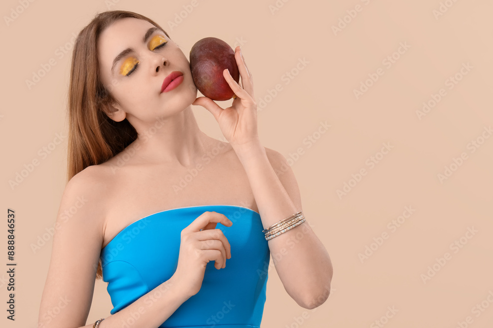 Beautiful young woman with sweet mango fruit on beige background