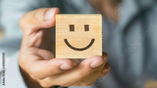 A hand showcasing a wooden block with a smiling face symbol