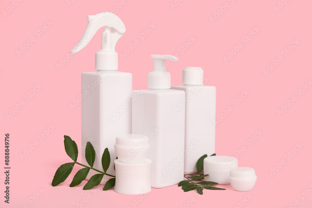 Composition with bottles, jars of cosmetic products and twigs on pink background