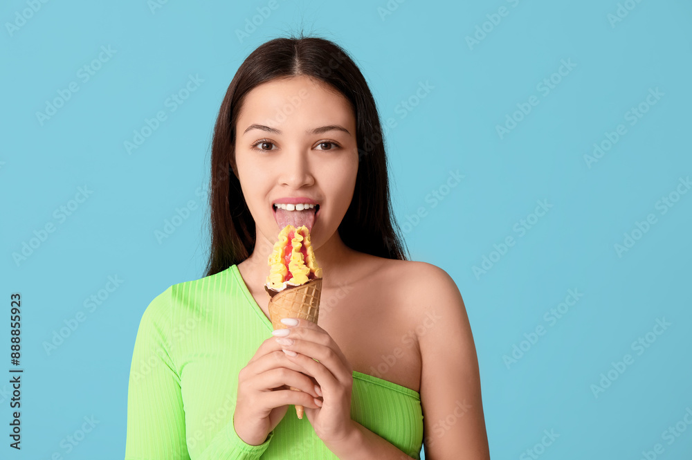 Beautiful Asian woman with mango ice-cream on blue background