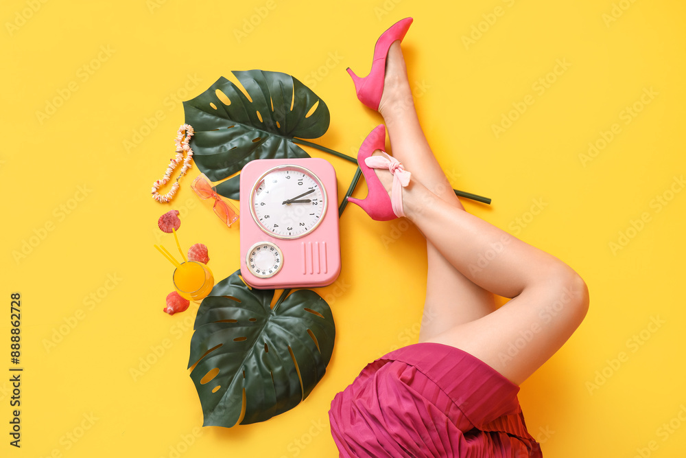 Young woman with clock, glass of juice, sunglasses and leaves on yellow background Young woman with clock, glass of juice, sunglasses and leaves on yellow background