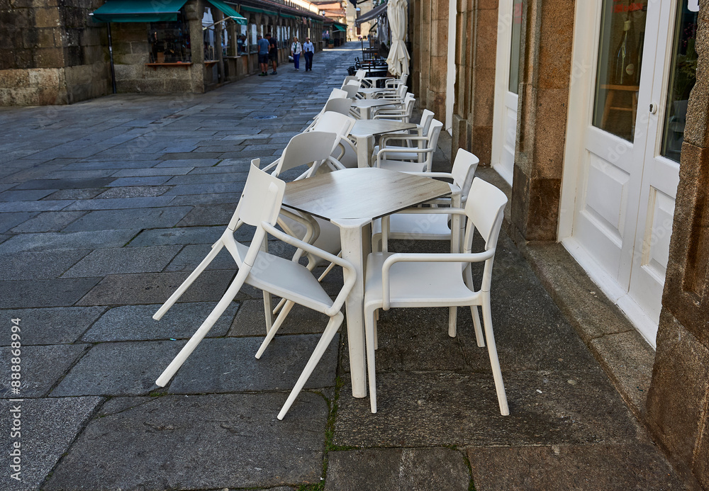 Naklejka premium empty plastic tables and chairs on the street next to the closed bar