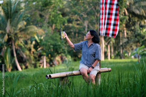 Woman enjoying cold tea in the breezy rice field in the afternoon photo