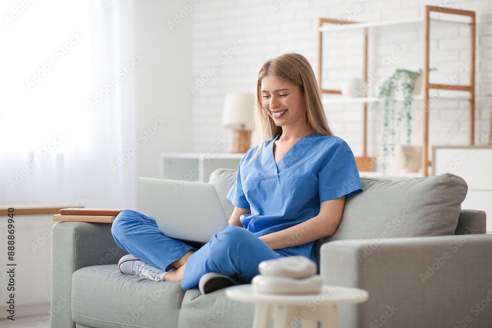 Female medical intern with laptop on sofa in living room Female medical intern with laptop on sofa in living room