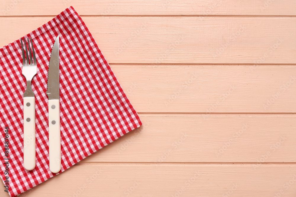 Table setting with napkin, fork and knife on beige wooden background Table setting with napkin, fork and knife on beige wooden background