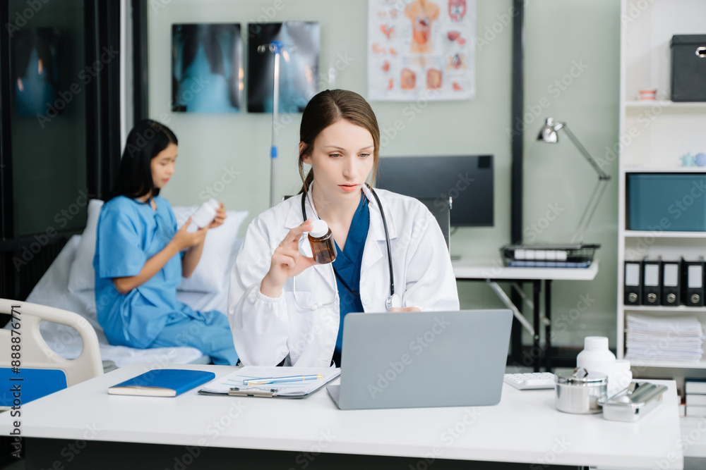 Young female doctor in white medical uniform using laptop and tablet talking video conference call at desk,Doctor sitting at desk