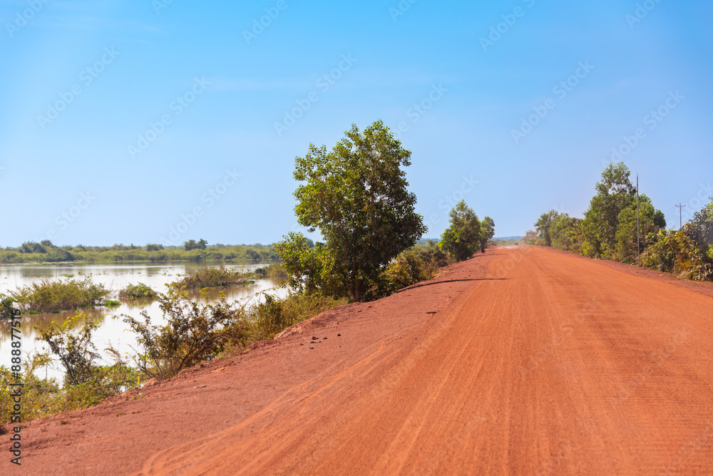 Naklejka premium Country dirt road of red sand in Cambodia with bikes