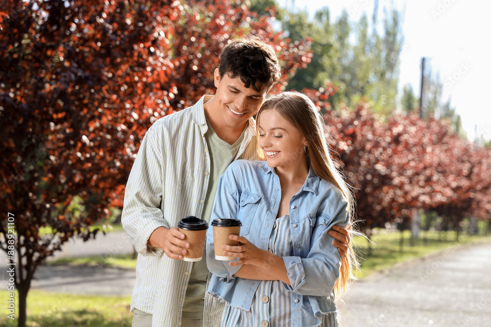 Beautiful young happy couple with cups of coffee in summer park Beautiful young happy couple with cups of coffee in summer park