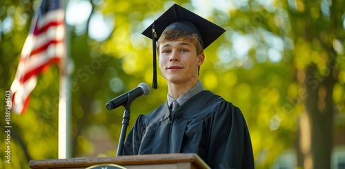 Graduate Student Speaking at Outdoor Ceremony With American Flag