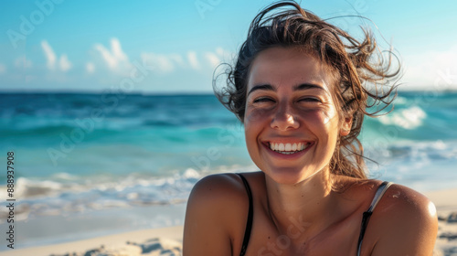 A woman with a cheerful smile, relaxing on a sandy beach with the ocean in the background.