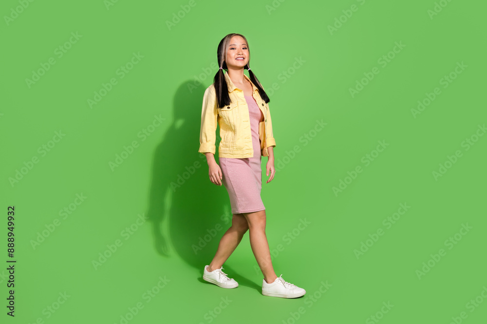 Full size profile photo of nice young girl walk empty space wear jacket dress isolated on green color background Full size profile photo of nice young girl walk empty space wear jacket dress isolated on green color background