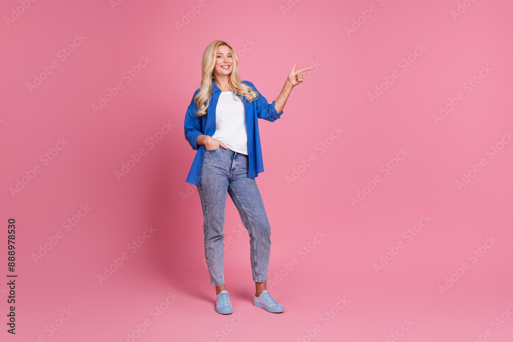 Full length photo of adorable lovely woman wear blue shirt pointing empty space isolated pink color background Full length photo of adorable lovely woman wear blue shirt pointing empty space isolated pink color background
