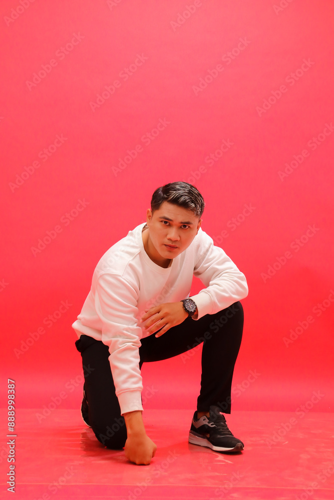 Full body of adult indonesia man wearing elegant white sweater squatting with hands on the floor. for fashion content, advertising, business Full body of adult indonesia man wearing elegant white sweater squatting with hands on the floor. for fashion content, advertising, business