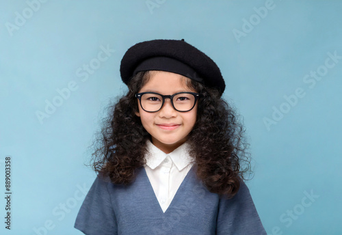 黒のベレー帽と黒縁メガネをかけた笑顔の少女 ブルーの背景