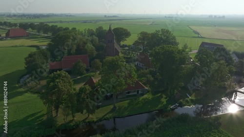 Aerial view of peaceful countryside village with church and river, Allingawier, Friesland, Netherlands. photo