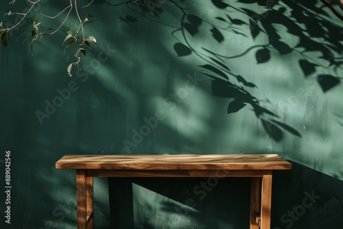 Minimalist Wooden Table with Leaf Shadows Against a Dark Green Wall photo