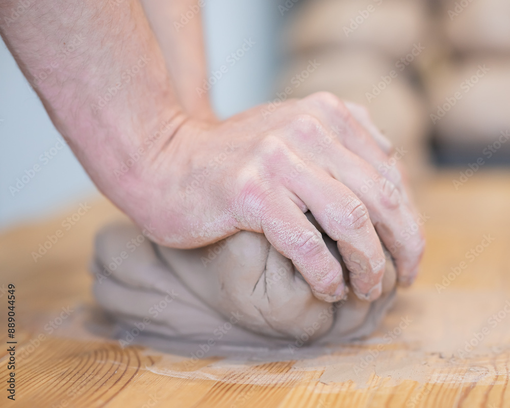 A potter kneads clay before using it in the workshop. Close-up of a man's hands. 