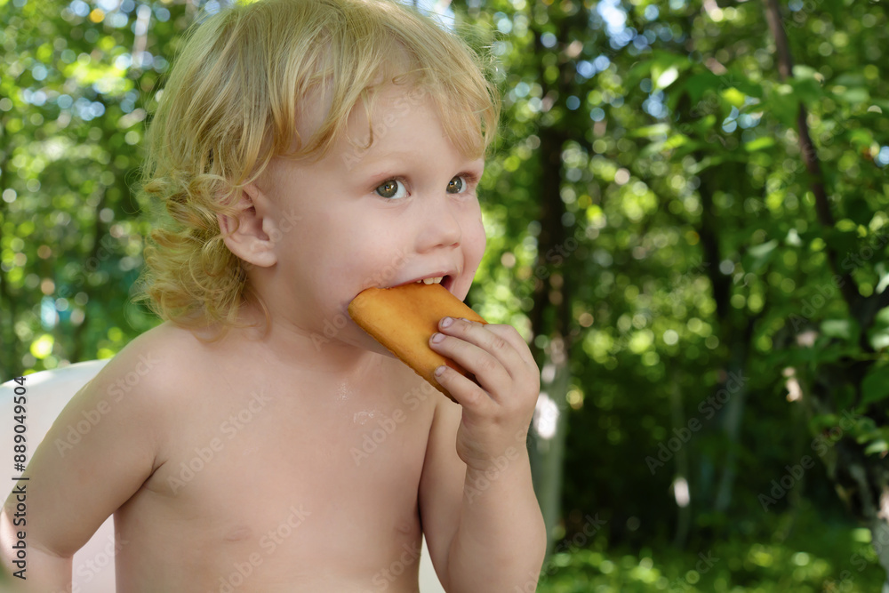 Adorable curly-haired child joyfully indulging in a tasty cookie, surrounded by the verdant foliage of garden trees on a warm, sun-dappled summer afternoon. Adorable curly-haired child joyfully indulging in a tasty cookie, surrounded by the verdant foliage of garden trees on a warm, sun-dappled summer afternoon.