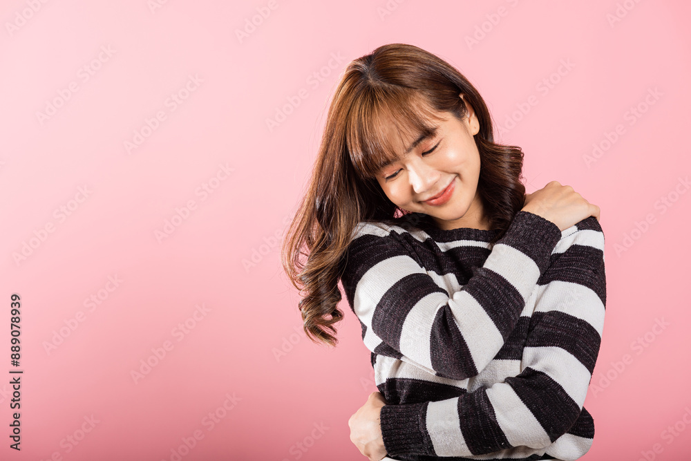 Happy beautiful young smiling Asian woman hugging herself remember a moment studio short isolated on pink background, Self care and self esteem concept, Lifestyle female love yourself carefree