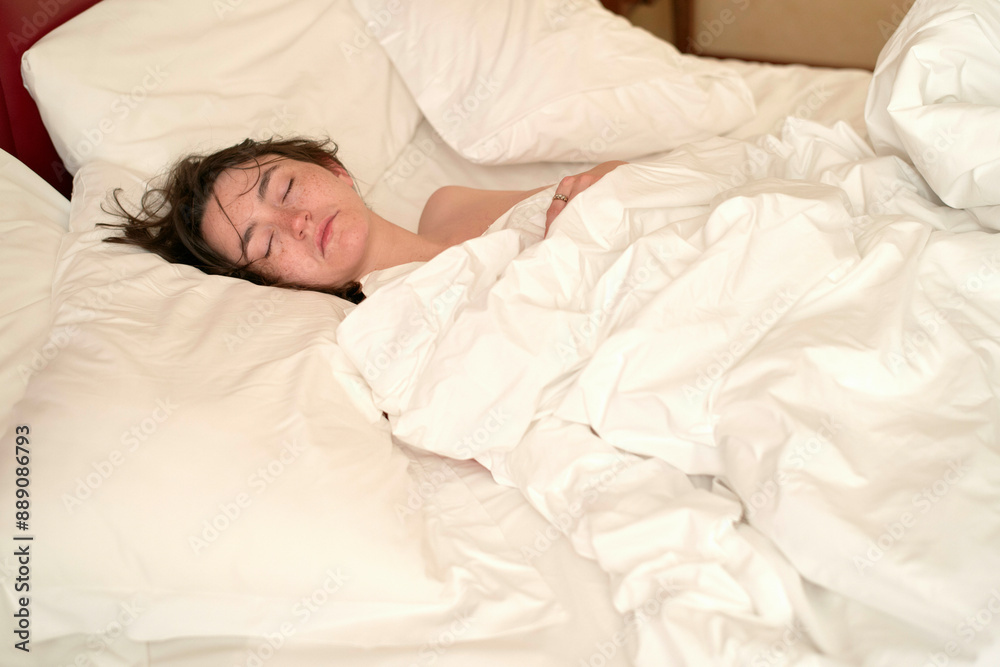 A person is peacefully sleeping in a bed, covered with a white duvet in a cozy bedroom setting. A person is peacefully sleeping in a bed, covered with a white duvet in a cozy bedroom setting.