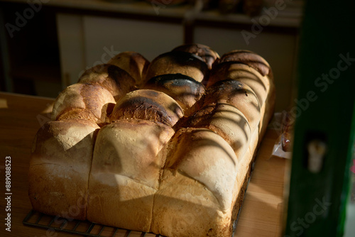 Freshly baked loaves of bread cooling on a wire rack in warm sunlight.