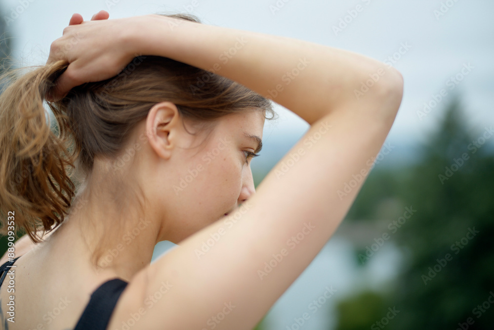 Woman with her hair tied up, viewed from the side against a blurred natural background. Woman with her hair tied up, viewed from the side against a blurred natural background.