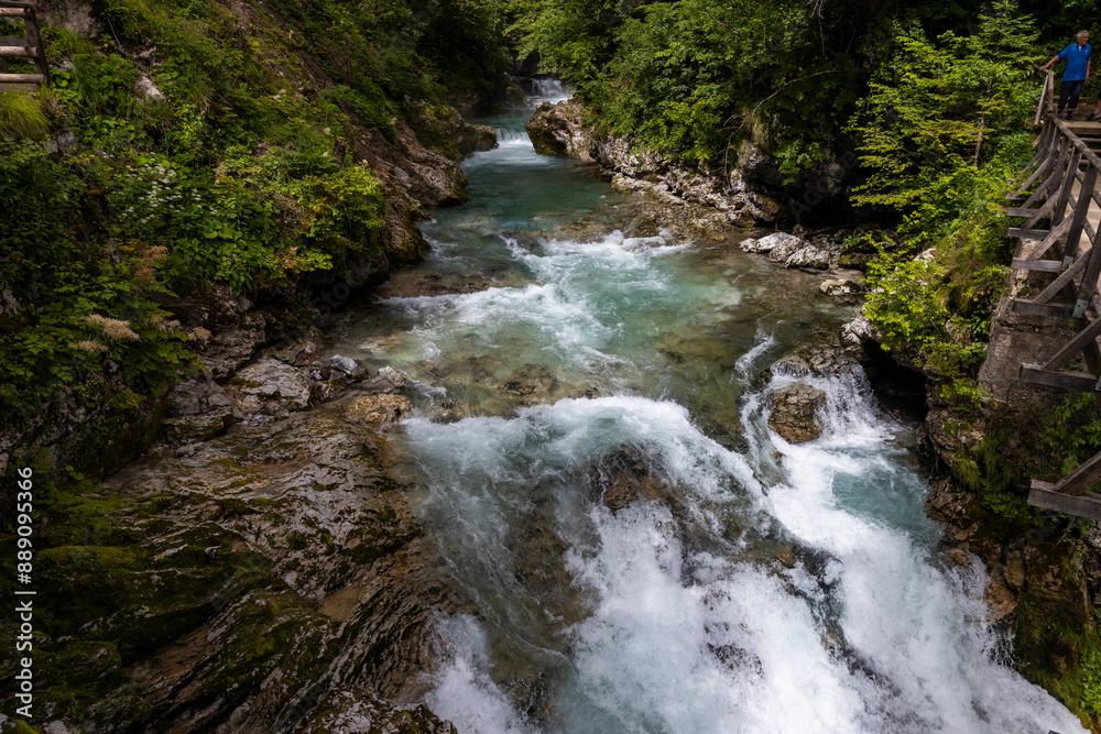 Obraz premium Vintgar Gorges Park a few km from Lake Bled, Slovenia. Wooden walkways accompany the path above the river rapids and waterfalls. River hits rocks and creates fog.Adventure family holidays. Freshness.
