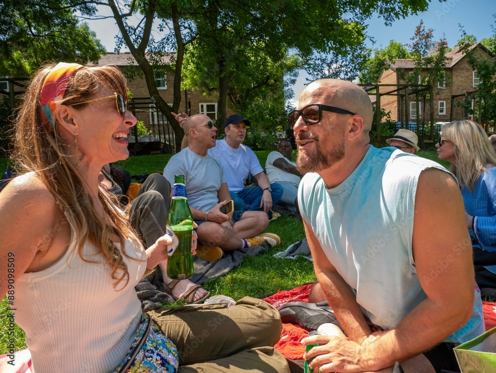 Friends enjoy a sunny picnic in the park, laughing and sharing a bottle of wine on a vibrant green lawn. Friends enjoy a sunny picnic in the park, laughing and sharing a bottle of wine on a vibrant green lawn.