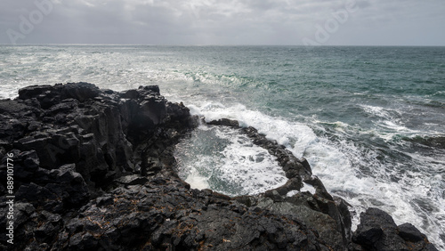 Waves clashing on the black lava rocks of reykjanes coastline and brimketill lava pool on iceland in summer photo