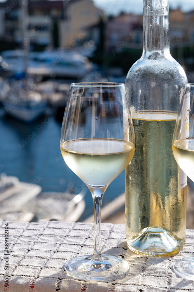 Obraz premium Glasses of cold white Cote de Provence wine in yacht harbour of Port Grimaud, summer vacation on French Riviera in Provence, France, wine tasting