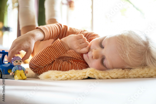 Child playing with toy figures on a fluffy rug indoors. photo