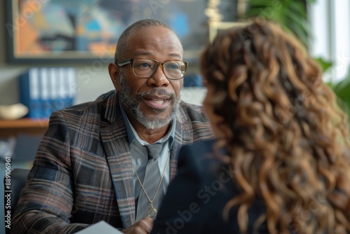 HR specialist conducting a performance review meeting with an employee in a private office. The discussion is focused and constructive, with the specialist providing feedback and guidance while the
