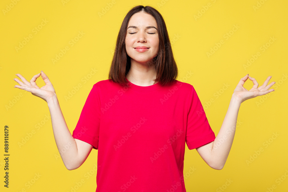 Young woman wear pink t-shirt casual clothes hold spreading hands in yoga om aum gesture relax meditate try to calm down isolated on plain yellow orange background studio portrait. Lifestyle concept.