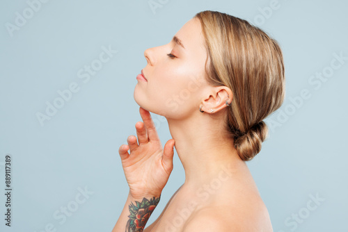 Side view half naked topless young woman 20s with nude make up raise up head with close eyes touching neck isolated on plain pastel blue background. Skin care healthcare cosmetic procedures concept. photo