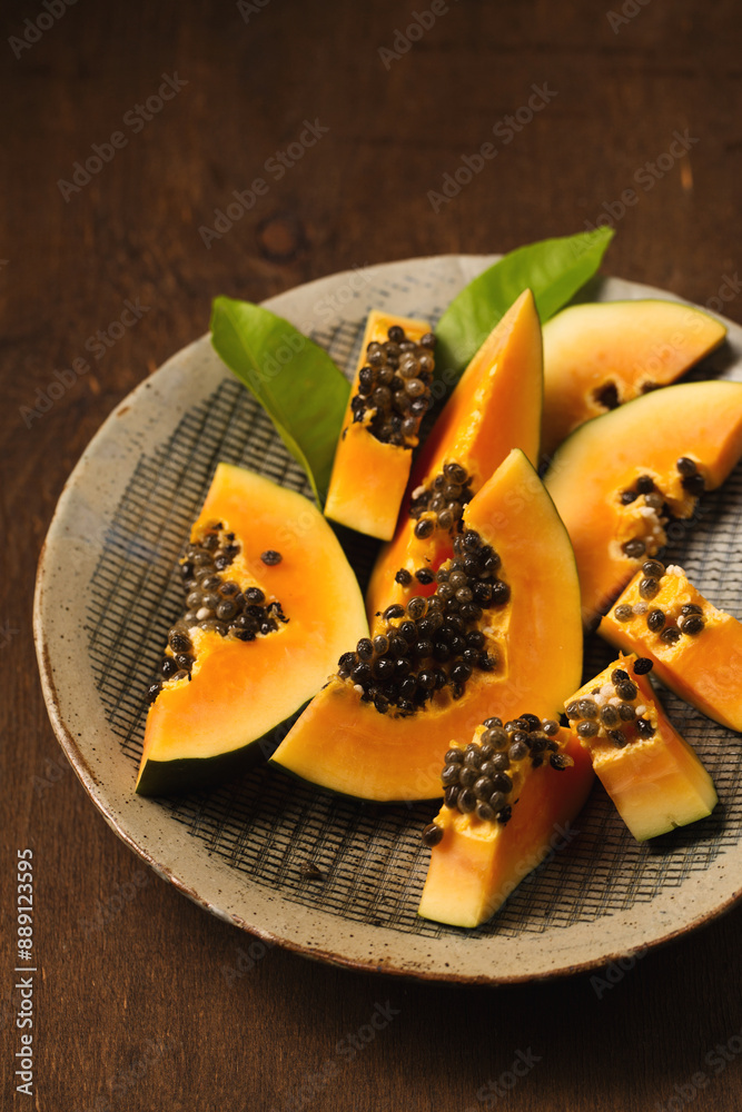 Sliced ripe papaya in a handmade ceramic bowl on a wooden table Sliced ripe papaya in a handmade ceramic bowl on a wooden table