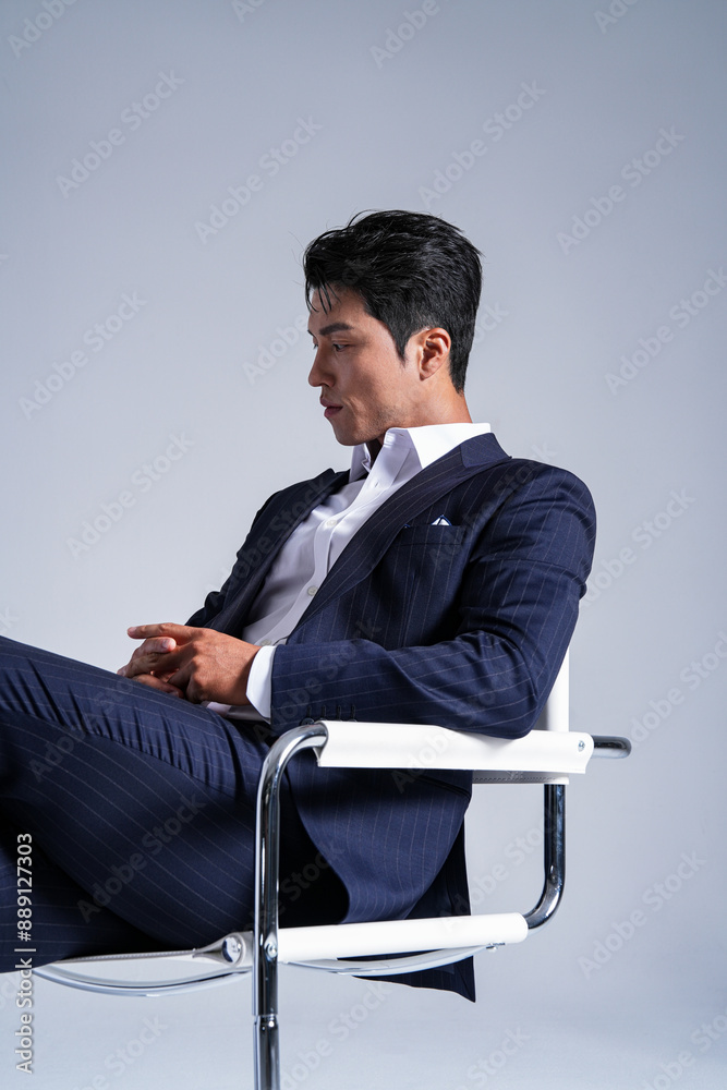 椅子に座ったスーツを着た男性のスタイリッシュなビジネスポートレート