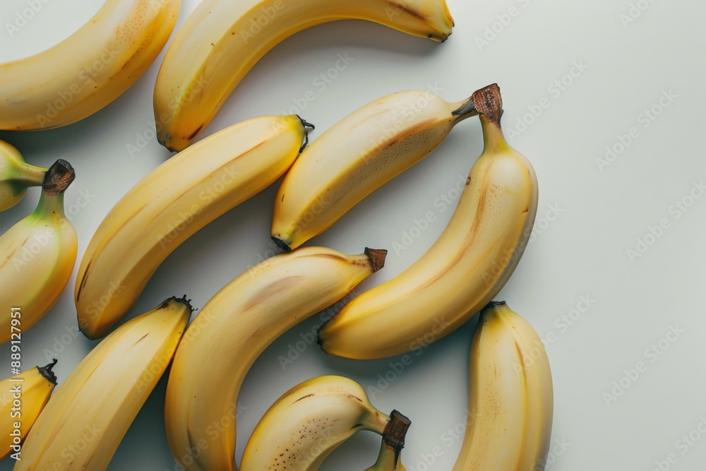 A neat arrangement of ripe bananas on a clean white surface, perfect for a healthy snack or fruit display. The bananas are at their peak ripeness, with a few slight brown spots. A neat arrangement of ripe bananas on a clean white surface, perfect for a healthy snack or fruit display. The bananas are at their peak ripeness, with a few slight brown spots.