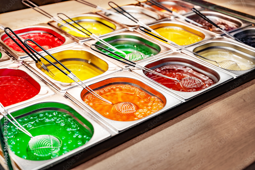Confectionery display case with jelly substance in metal trays. sweet shop, street food, colorful sweet food, magic products or bubble tea .
