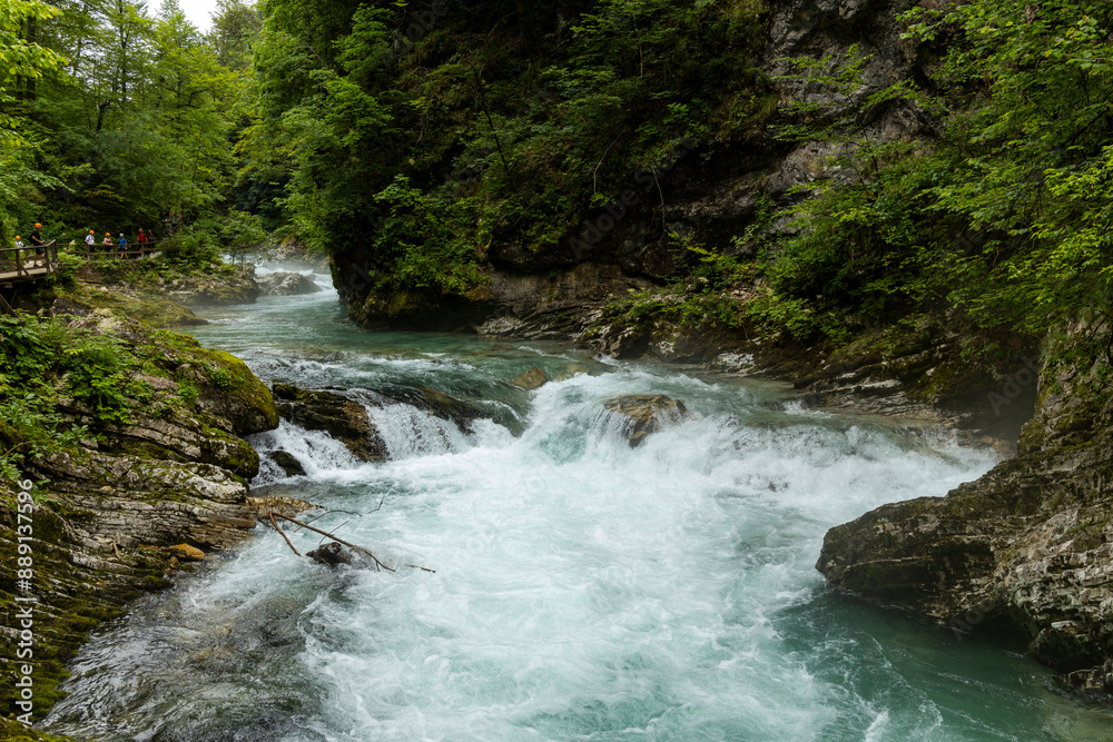 Obraz premium Vintgar Gorges Park a few km from Lake Bled, Slovenia. Wooden walkways accompany the path above the river rapids and waterfalls. River hits rocks and creates fog.Adventure family holidays. Freshness.
