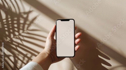 a studio photo of a hand holding an iphone with green screen, A beige seamless background with a sunlight feel. Dramatic lighting,