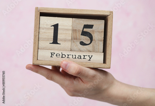Wallpaper Mural Woman's hand holds wooden block calendar with the date February 15 on pink concrete background Torontodigital.ca