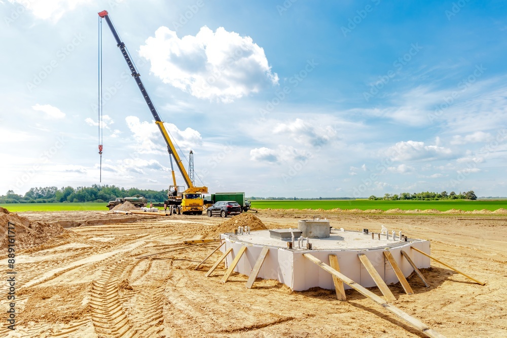 Obraz premium A construction site with a lifting crane and workers installing water pipes.