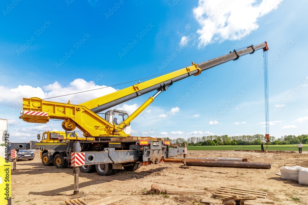 A construction site with a lifting crane and workers installing water pipes. A construction site with a lifting crane and workers installing water pipes.
