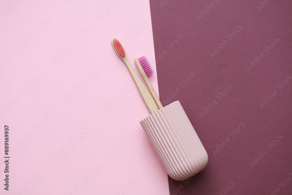 Eco bamboo toothbrushes in plastic organizer case on pink burgundy background